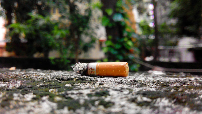Discarded cigarette butt on pavement