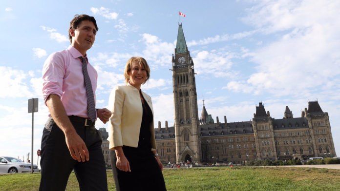 Prime Minister Justin Trudeau walks with Chief Science Advisor Mona Nemer in front of Canada's parliament