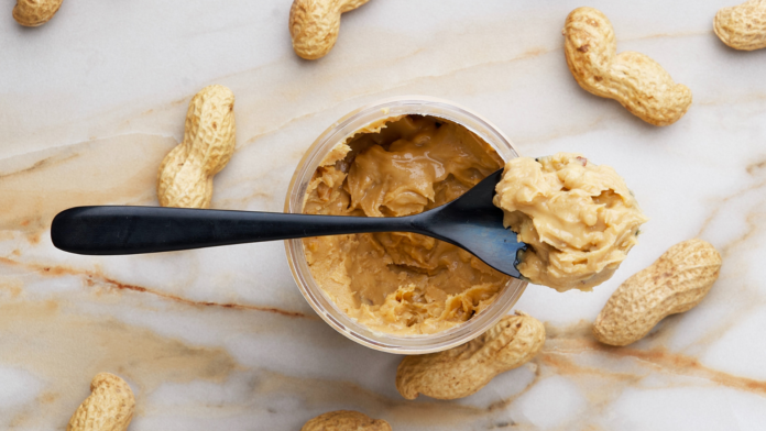 Spoon of peanut butter surrounded by monkey nuts