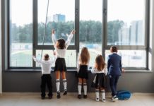 A group of children in school uniforms looking out the window at school.