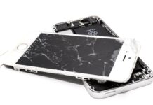 A broken cell phone. It is a white iPhone with a cracked screen.
