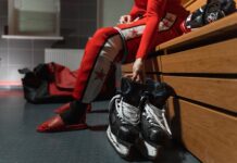 A hockey player sitting on the bench in the change room.
