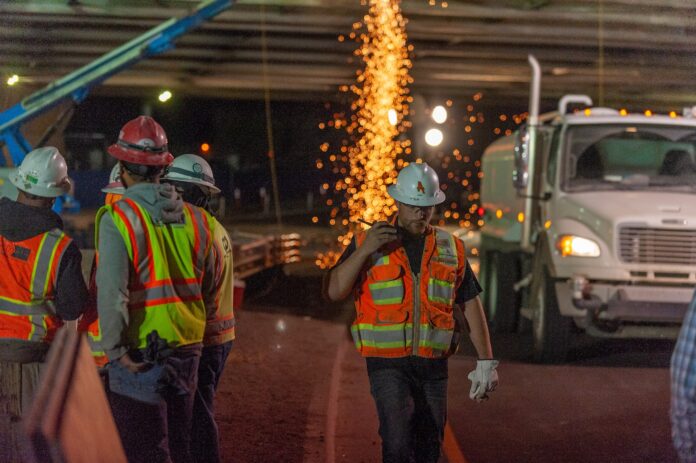 A group of construction workers working during the night at a construction site.
