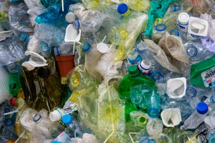 A collection of plastic waste, including empty plastic water bottles, yogurt containers, and plastic bags.