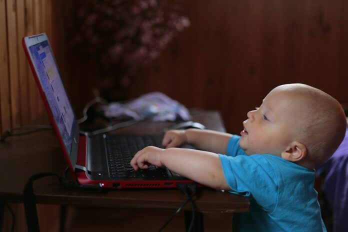 A baby looking at a laptop.